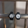 Two Casio G-Shock watches on a metal surface with a blurred background