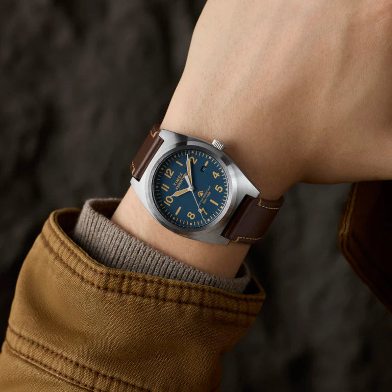 Close-up of a wrist wearing a watch with a brown leather strap and blue dial.